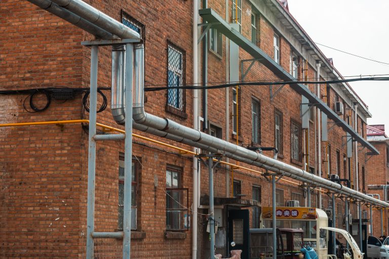 Commercial Plumbing Data Now Integrates into Building Automation Systems 2 Exterior view of brick building with exposed industrial pipes and utility lines