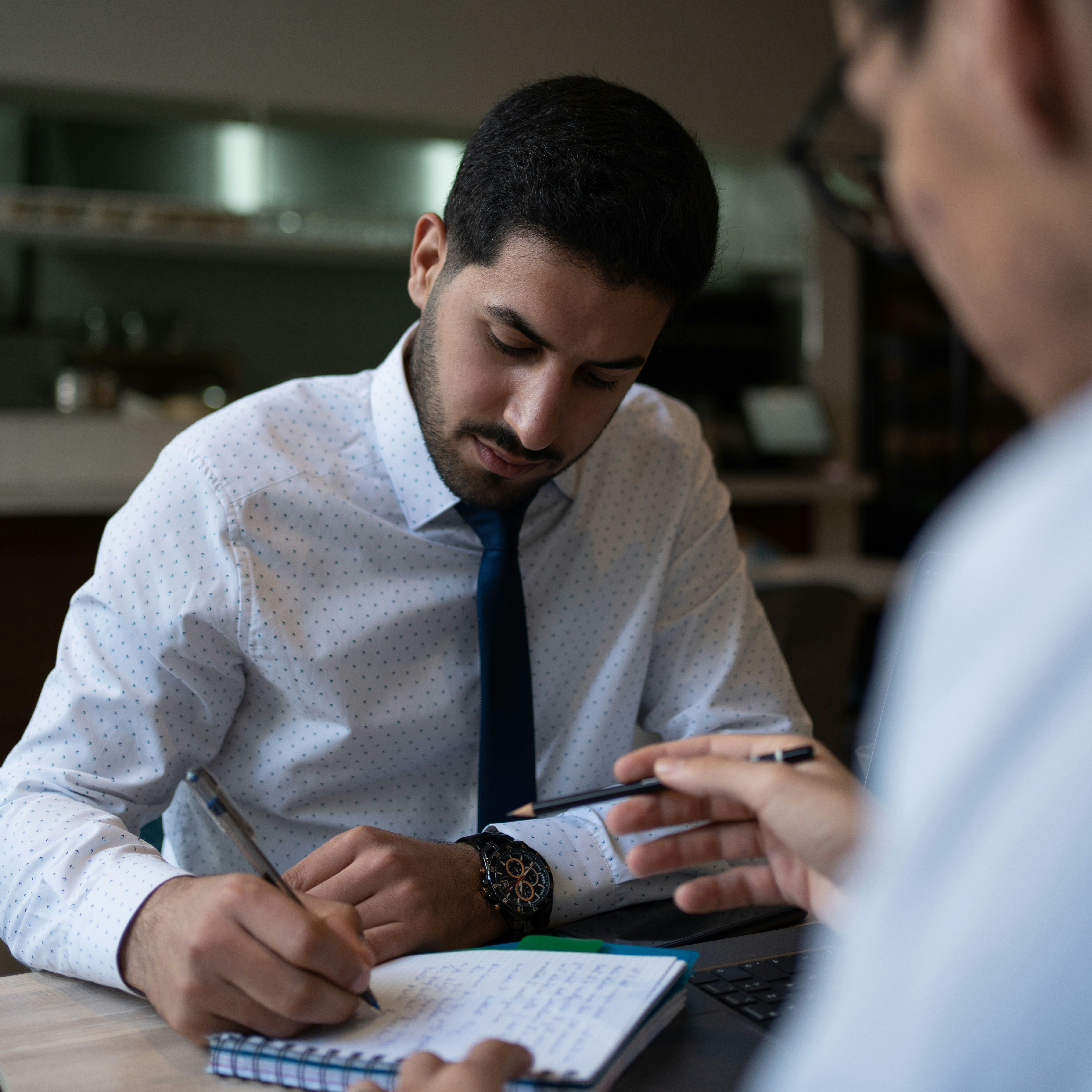 A professional reviewing documents and taking notes during a meeting, representing the process of comparing vehicle protection providers such as CarGuard Administration Inc.