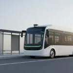 Autonomous electric shuttle at a minimalist curbside stop with a softly blurred city skyline.