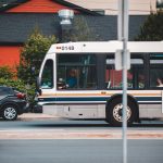 A white public transit bus travelling along an urban street