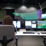 Female engineer managing multiple screens during a technology simulation in a control room