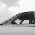 Close-up of rain-speckled airplane window in grayscale, showcasing aviation detail