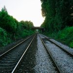 Illustrative stock photo of railway tracks running through greenery beneath a bridge